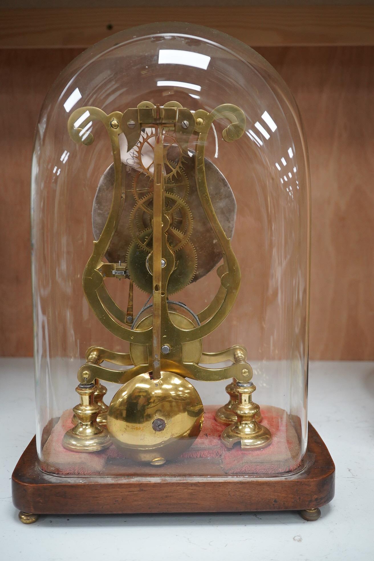 A late 19th century brass skeleton timepiece, the silvered chapter ring with Roman numerals, on a stand, under a glass dome, 37cm high. Condition - pendulum adjustment needed